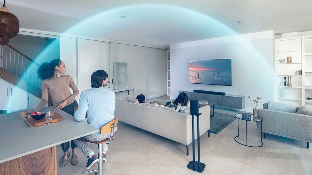 Salon z telewizorem BRAVIA i systemem audio; niebieski łuk ilustruje rozchodzenie się dźwięku przestrzennego z głośników wokół widzów